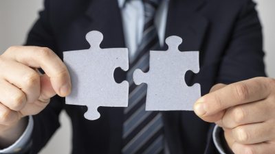 empresario-sosteniendo-dos-piezas-rompecabezas