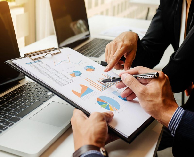 Business concept. Business people discussing the charts and graphs showing the results of their successful teamwork. Selective focus.